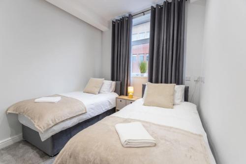 スウィンドンにあるFlat B Commercial Road, 3 Bedrooms, Sleeps 5, Located in town centreの窓のある小さな部屋にベッドが2つある