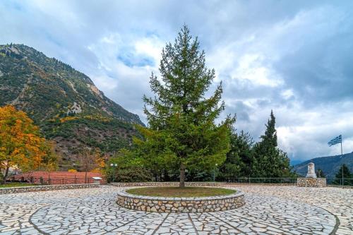 a tree in a stone circle in front of a mountain at Villa Kleino - 30 min from Meteora in Kalabaka