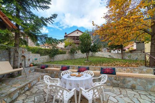 a patio with a table and chairs and a garden at Villa Kleino - 30 min from Meteora in Kalabaka