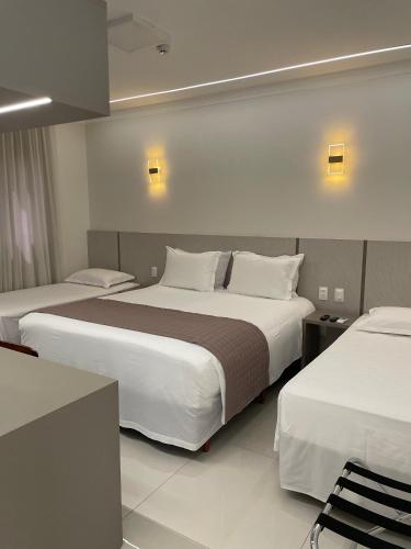 a hotel room with two beds and two chairs at Hotel Jardim in Jardim
