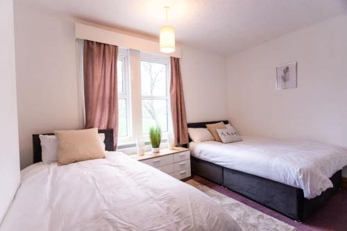 una camera da letto con due letti e una finestra di Edinburgh Street, Sleeps 9, 4 Bedrooms, Wifi, Long Stay Disc a Upper Stratton