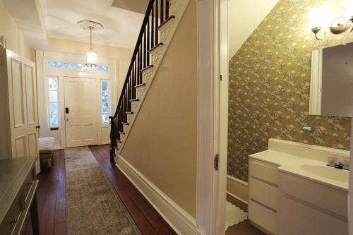 ein Badezimmer mit einer Treppe, einem Waschbecken und einem Spiegel in der Unterkunft Oglethorpe Manor Main House in Savannah