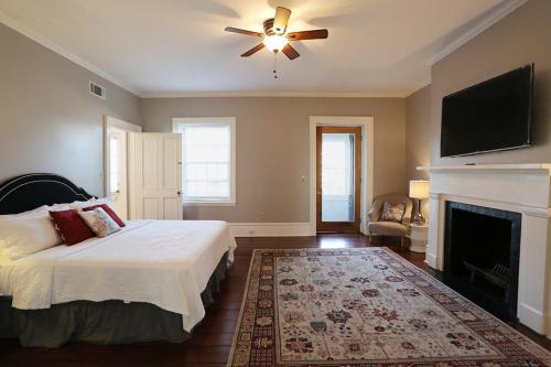 Schlafzimmer mit einem Bett, einem Deckenventilator und einem Kamin in der Unterkunft Oglethorpe Manor Main House in Savannah