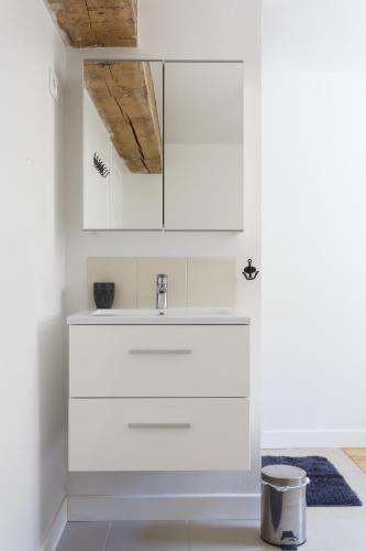 La salle de bains est pourvue de placards blancs et d'un lavabo. dans l'établissement LE GARDEN FAMILY - RANDO ESCALADE- Gîte avec Jardin spacieux - Confort & Wifi - Parking privé - Golf et château à 15 minutes, à Achères-la-Forêt