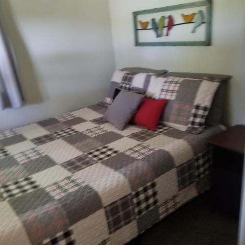 a bedroom with a bed with a blanket and pillows at Castaways Cottage on Croton Pond #2 in Newaygo