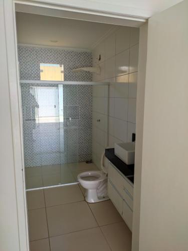 ein Badezimmer mit Toilette und Glasdusche in der Unterkunft Casa na praia de Jatobá in Barra dos Coqueiros