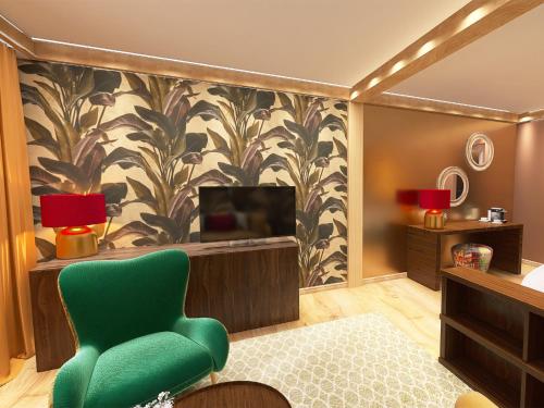 a living room with a green chair and a television at Alpenhotel St.Christoph in Sankt Christoph am Arlberg