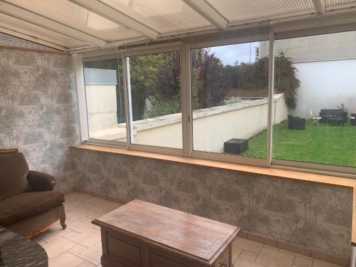 - un salon avec des fenêtres, un canapé et une table dans l'établissement Maison 6 personnes veranda et jardin, à Cherbourg en Cotentin