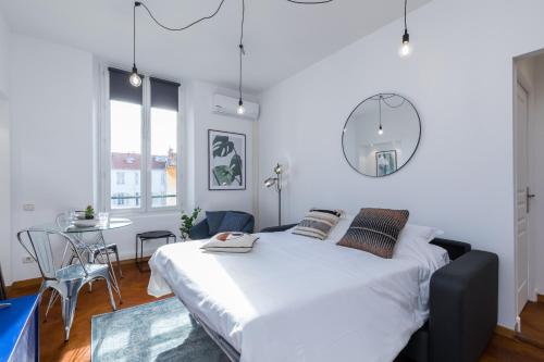 une chambre blanche avec un grand lit et une table dans l'établissement 7 MEDECIN - Place Massena - Central 2p - Lumineux - Climatise, à Nice