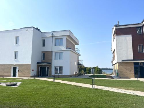 a large white building next to a grass field at Apartamenty Na wzgórzu in Ińsko
