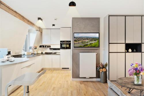 a kitchen with white cabinets and a tv on the wall at Modern Elegance in historical City Center in Trier