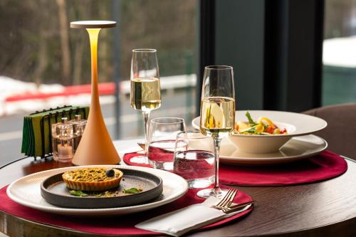 a table with a plate of food and glasses of wine at Hotel Simona Halep - Poiana Brasov in Poiana Brasov