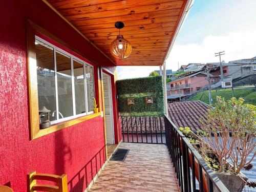 a red house with a wooden ceiling and a balcony at Apartamento Nuvem · Apartamento Nuvem 15 min centrinho in Campos do Jordão