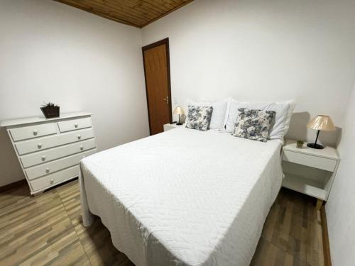 a white bedroom with a white bed and a dresser at Apartamento Nuvem · Apartamento Nuvem 15 min centrinho in Campos do Jordão