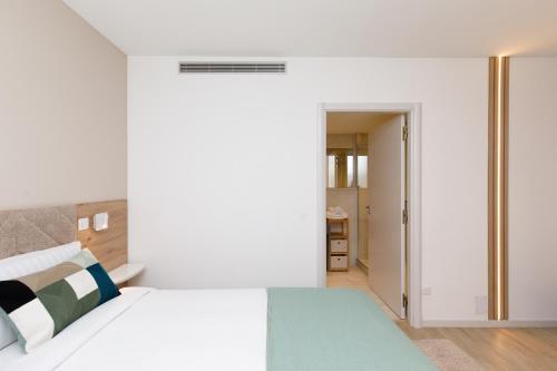 a white bedroom with a bed and a hallway at Côté Croisette LUXE - 2BdR 2 bthR 2 toilets -Terrace, AC, parking & lift in Cannes