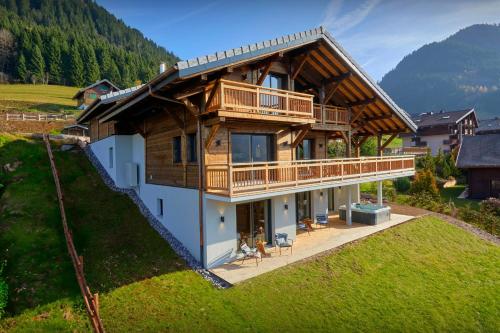 a large wooden house with a balcony on a hill at Chalet La Cachette - OVO Network in Châtel