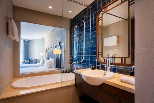 a bathroom with a sink and a tub and a mirror at Mandala Cham Bay Hotel Mũi Né in Mui Ne