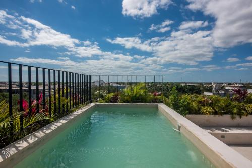 a swimming pool on the roof of a building with a sky at Bright 2BR Loft with Rooftop Pool in Best Tulum Downtown Location in Tulum