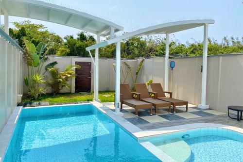 a pool with two chairs and a pergola next to a house at 阿爾法民宿AlphaVilla in Hengchun