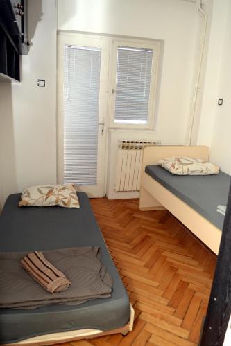 two beds in a room with wooden floors and windows at Vladimir Apartman in Lavci