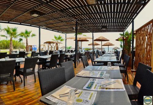 a dining room with tables and chairs and umbrellas at Bungalow on the sea - Moriani beach in Santa-Lucia-di-Moriani