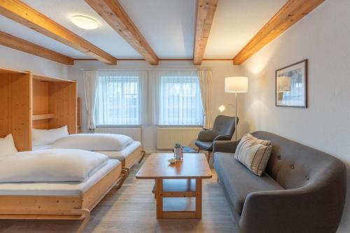 a living room with a couch and a bed and a table at Direkt am Deich - Ferienwohnung Föhr im Gästehaus Am Badedeich in Dagebüll