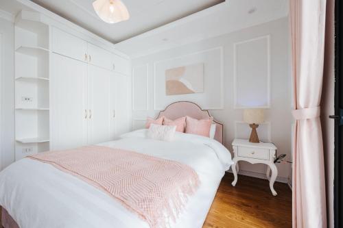 a white bedroom with a bed and a pink blanket at Soleil Residence Westlake Hanoi in Hanoi