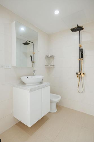 a white bathroom with a sink and a toilet at Soleil Residence Westlake Hanoi in Hanoi