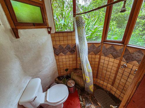 a bathroom with a toilet and a shower curtain at Cloudbridge Nature Reserve in Herradura