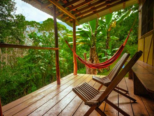 two chairs sitting on a porch with a hammock at Cloudbridge Nature Reserve in Herradura
