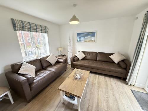 a living room with a couch and a coffee table at New England Cottage - Part of the The Bay Filey Holiday Village with pool, gym and direct beach access, pub, restaurant, tennis and meadows walks in Filey