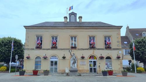 a building with a statue in front of it at La maison du Pays d'Auge in Troarn