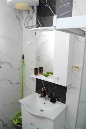 a bathroom with a white sink and a mirror at Simona Apartman in Bitola