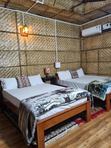 two beds in a room with a wall at Alohi The Cottage Homestay in Tezpur