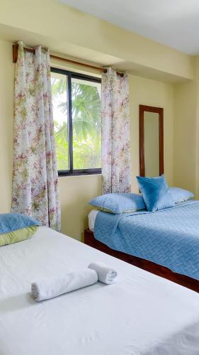 two beds in a room with a window at Hotel Turístico Marian in Las Terrenas