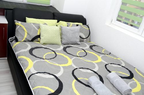 Cama con edredón y almohadas amarillos y grises en Simona Apartman, en Bitola