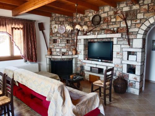 a living room with a stone wall with a tv at Tsampika's Traditional Stone Cottage in Siana in Siána