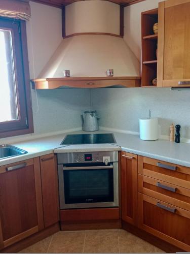 a kitchen with wooden cabinets and a stove top oven at Tsampika's Traditional Stone Cottage in Siana in Siána