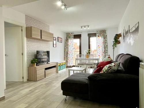 a living room with a black couch and a kitchen at Puente de la Reina de Teruel in Teruel