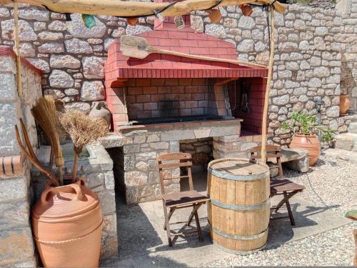 an outdoor brick oven with chairs and a barrel at Tsampika's Traditional Stone Cottage in Siana in Siána