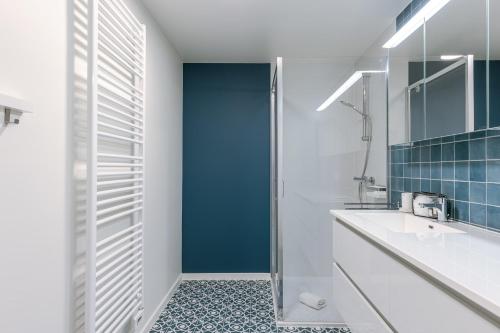 a bathroom with a white sink and a shower at Huswell - Modern apartment in city center in Blankenberge