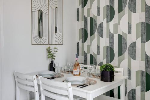 une table à manger avec des chaises blanches et un papier peint vert et blanc dans l'établissement Bluestay 203 - Charming Studio, à Bagnolet