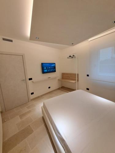 une chambre blanche avec un lit et une télévision au mur dans l'établissement H3V, à Tarente