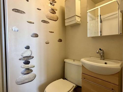 La salle de bains est pourvue de toilettes et de rochers sur le mur. dans l'établissement Appartement 2 pièces - 4 personnes - AR740-093, à Argelès-sur-Mer