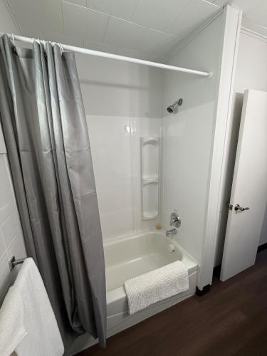 a white bathroom with a shower and a tub at New Country Motel in Swan River