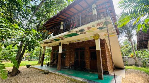 ein Gebäude mit einer Veranda in einem Park in der Unterkunft Hela Gedara Villa Beruwala in Beruwala