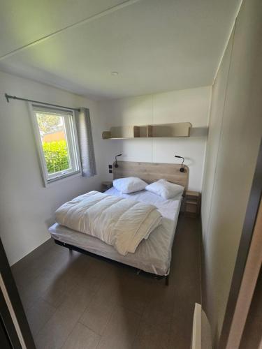a bedroom with a bed with white sheets and a window at loggia 29 in Biville-sur-Mer