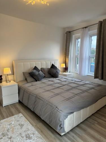 a bedroom with a large bed and two windows at 2 Bedroom luxury apartments in Bristol