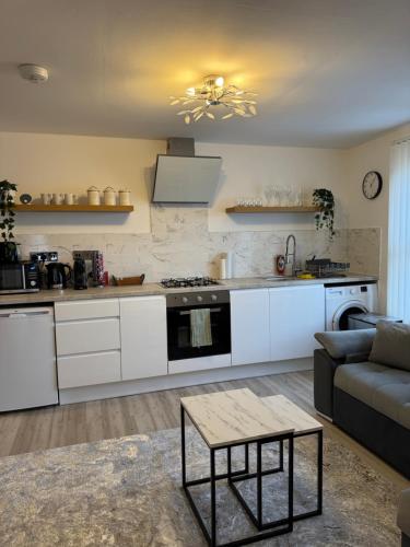 a kitchen with white cabinets and a couch and a table at 2 Bedroom luxury apartments in Bristol