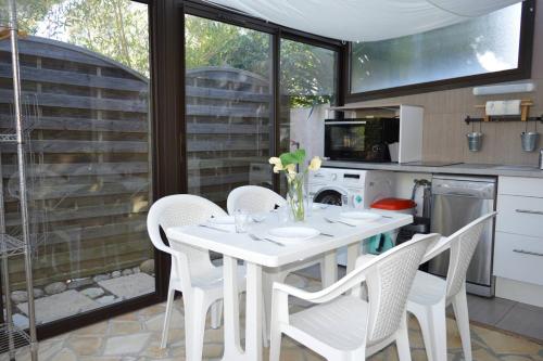 - une cuisine avec une table blanche et des chaises blanches dans l'établissement Maison 4 pièces ARGELES SUR MER AR300-027, à Argelès-sur-Mer
